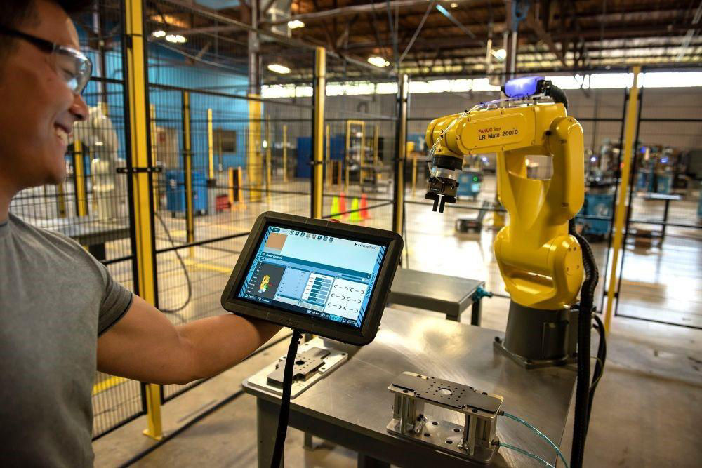 man standing in front of a portable monitor that controls robot