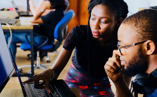 Two people of color reading a resume on a laptop.