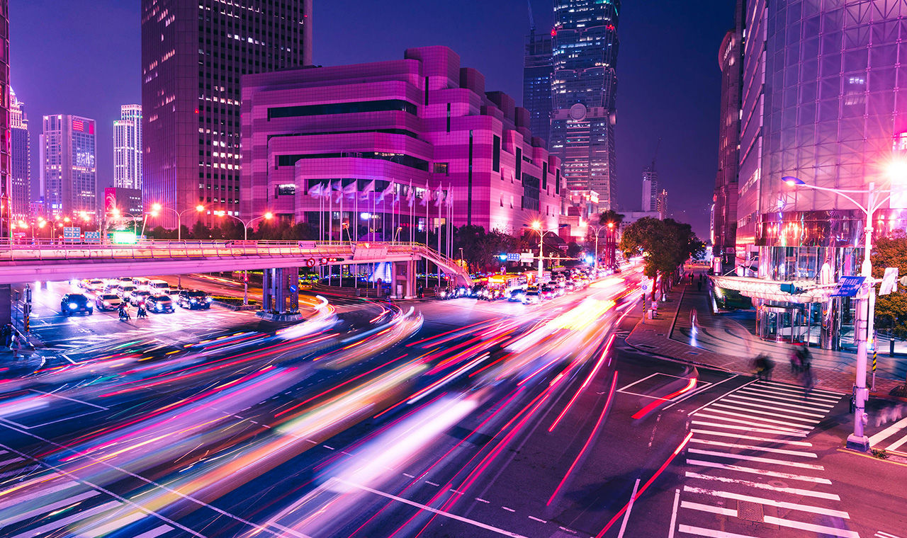 night view of lighted skyscrapers with beams of car lights