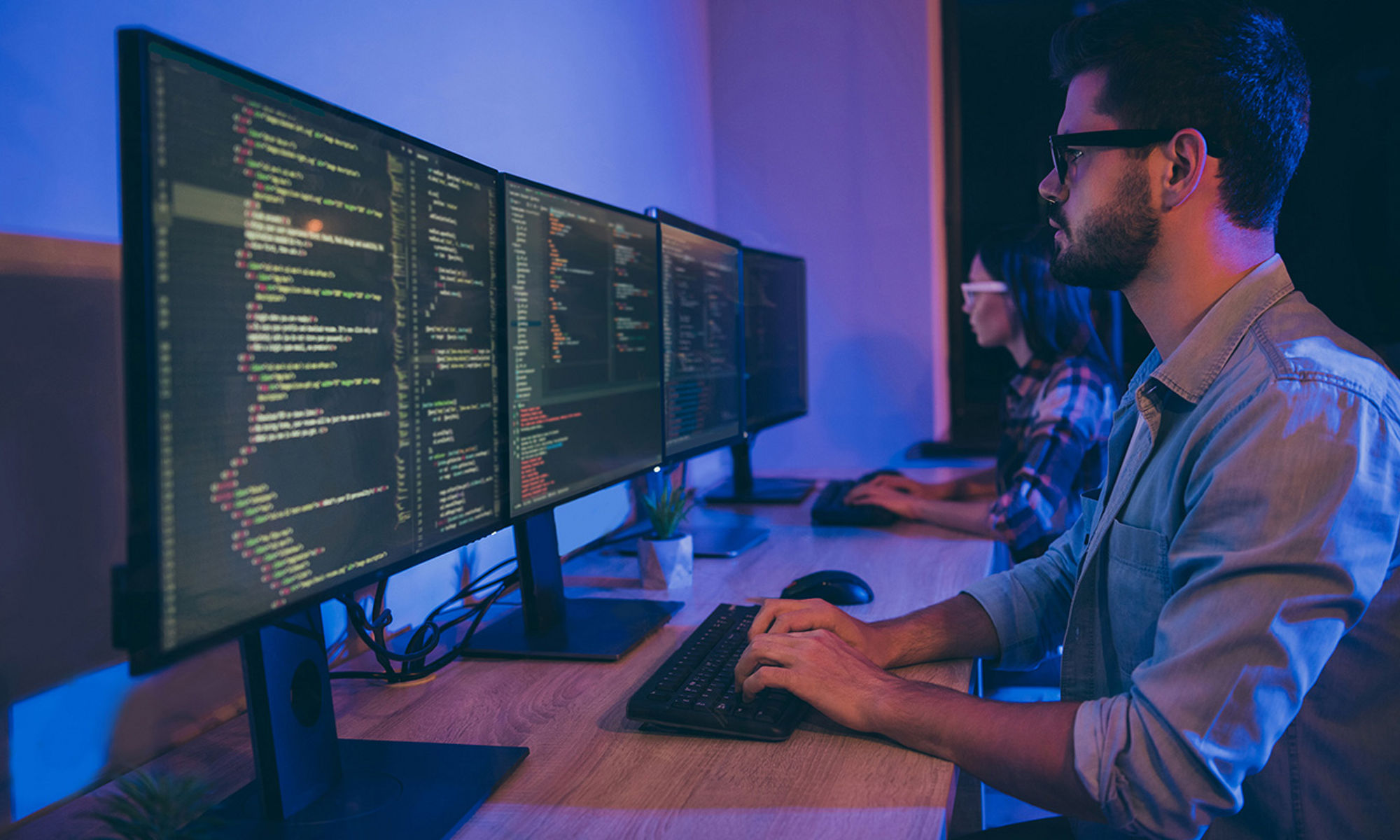 Coder looking at display on monitors