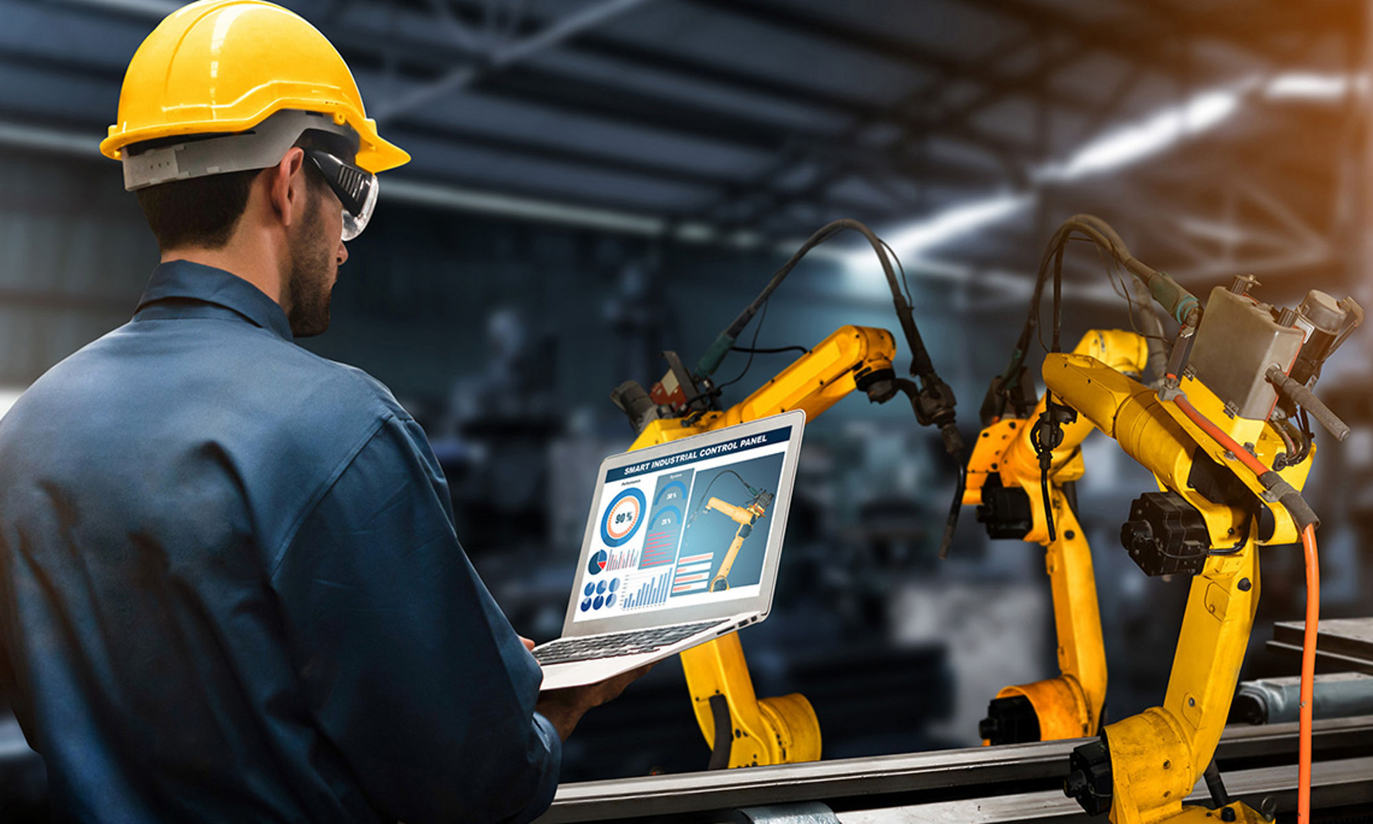 Man with yellow hard hat controlling robotic machine from a digital screen