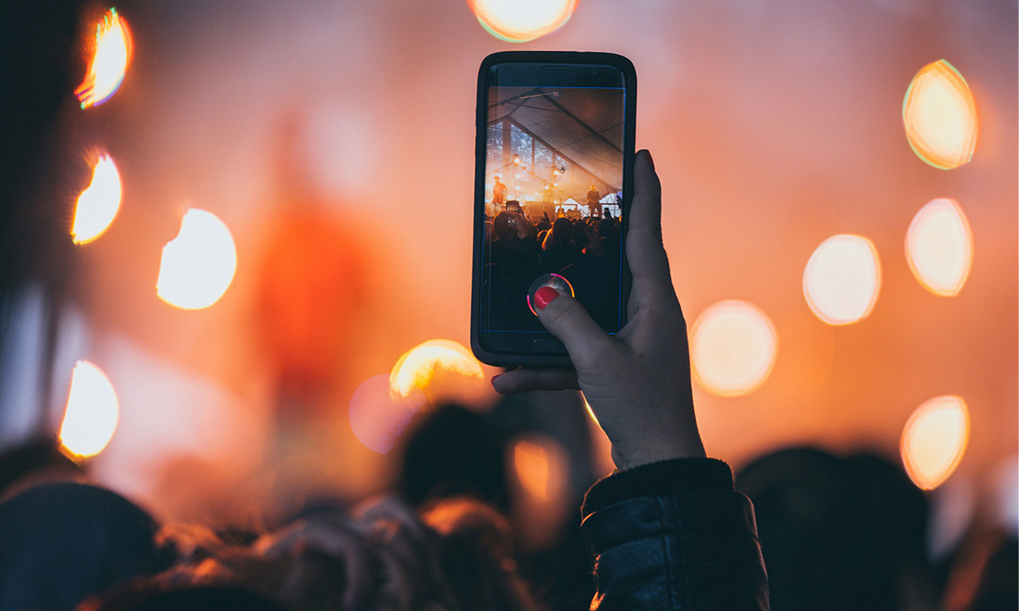 A hand with a mobile phone taking a photo at an event