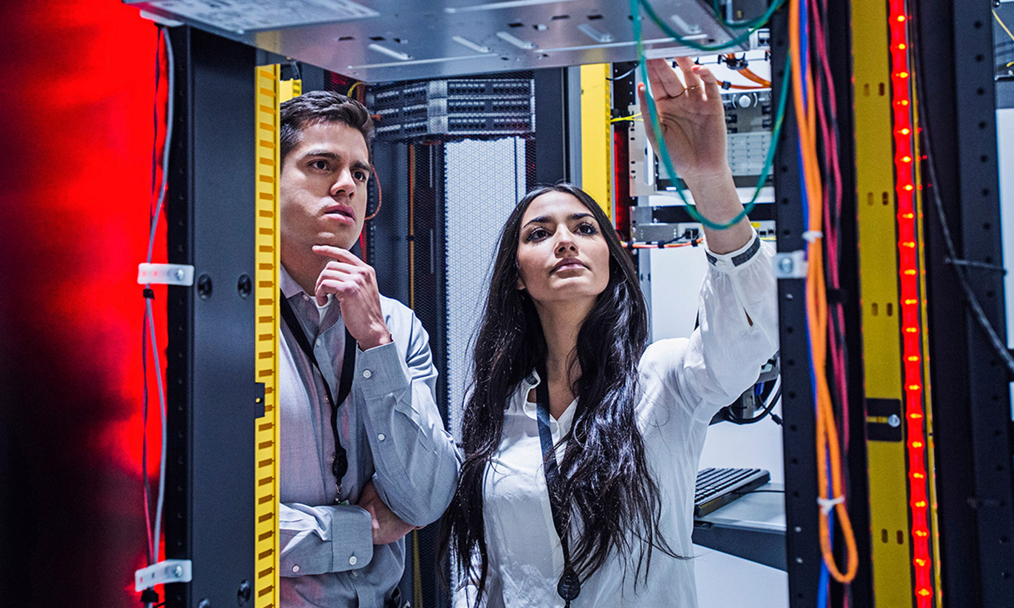 Two co-workers collaborating in a server room