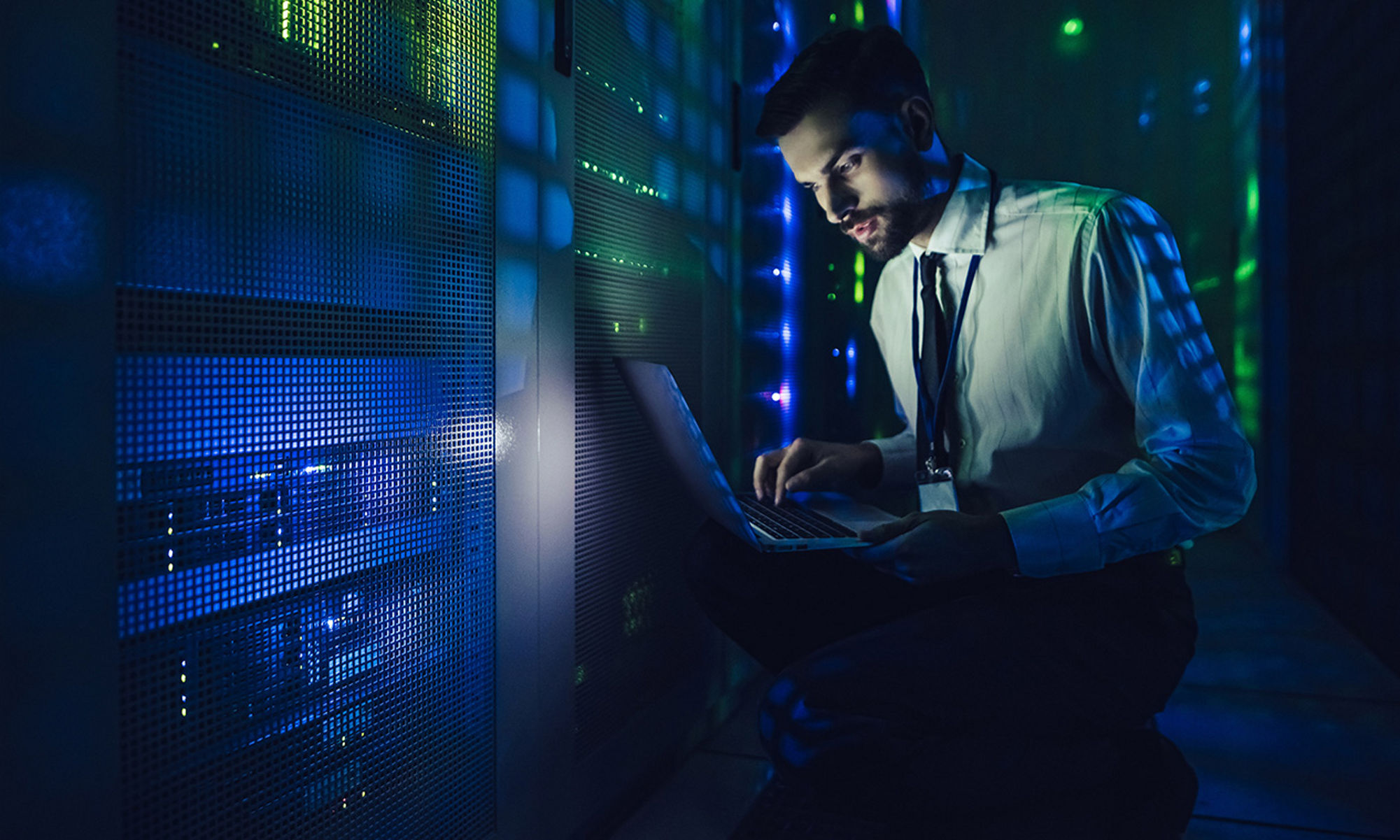 a man working with a laptop in a data center room