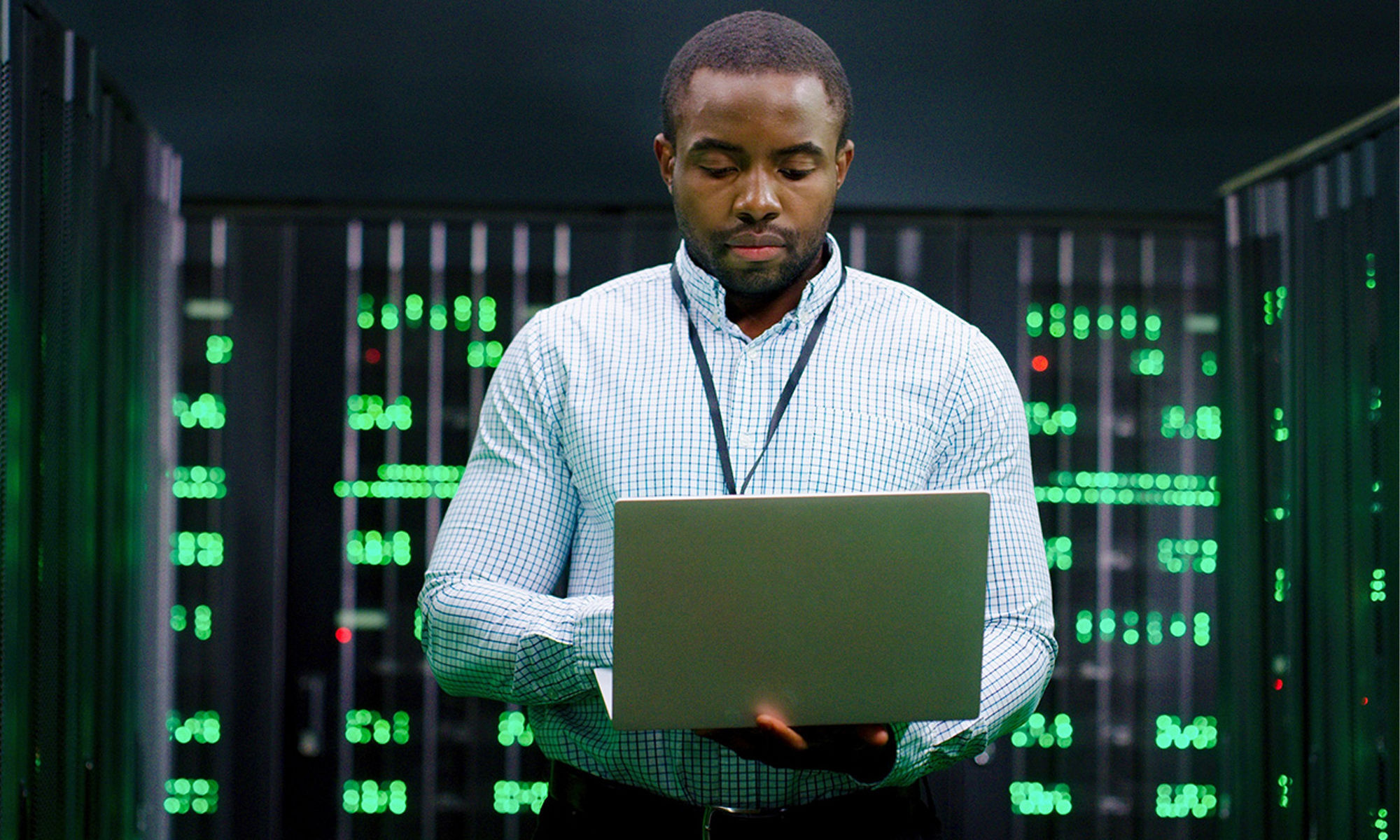 man using laptop in a data center server room
