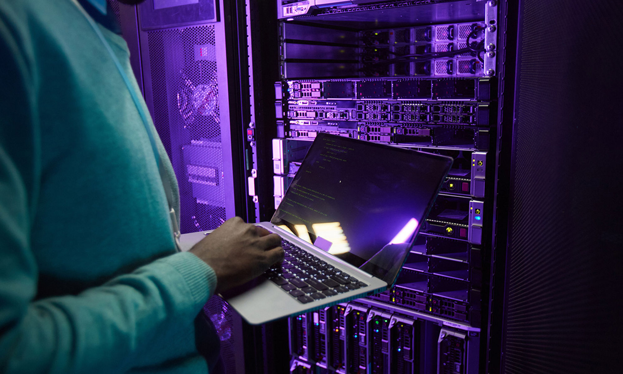 A technician using laptop standing at a server