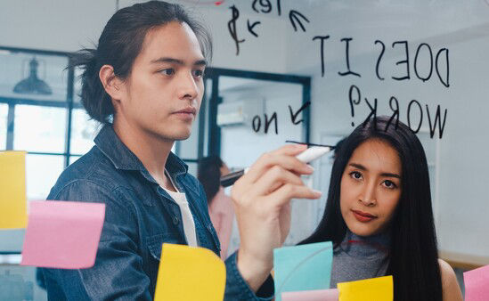 man writing on board while woman watches