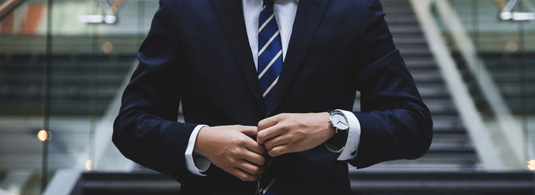 Man buttoning suit in front of stairs