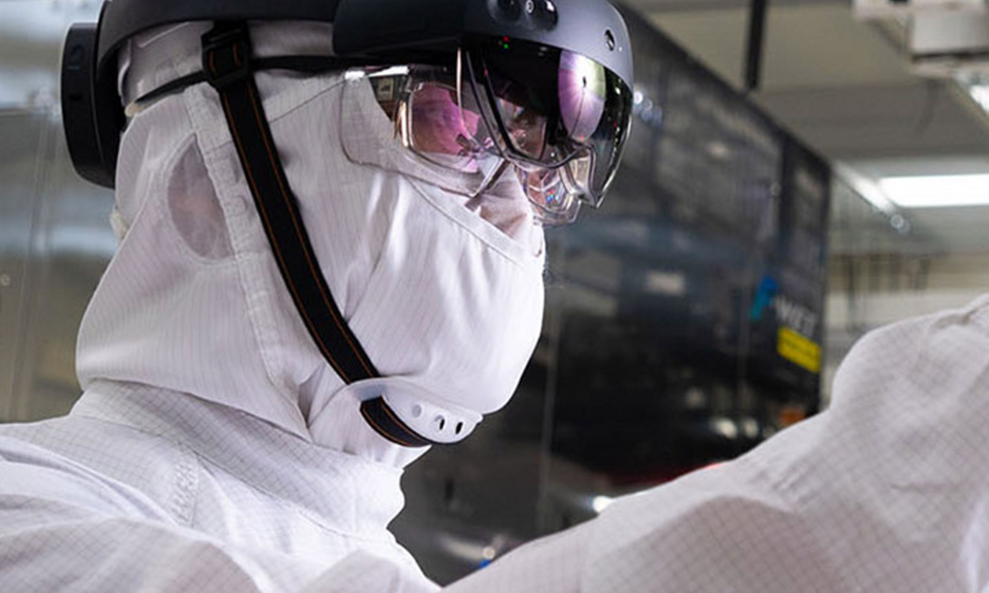 Person wearing bunny suit examining parts in manufacturing cleanroom 