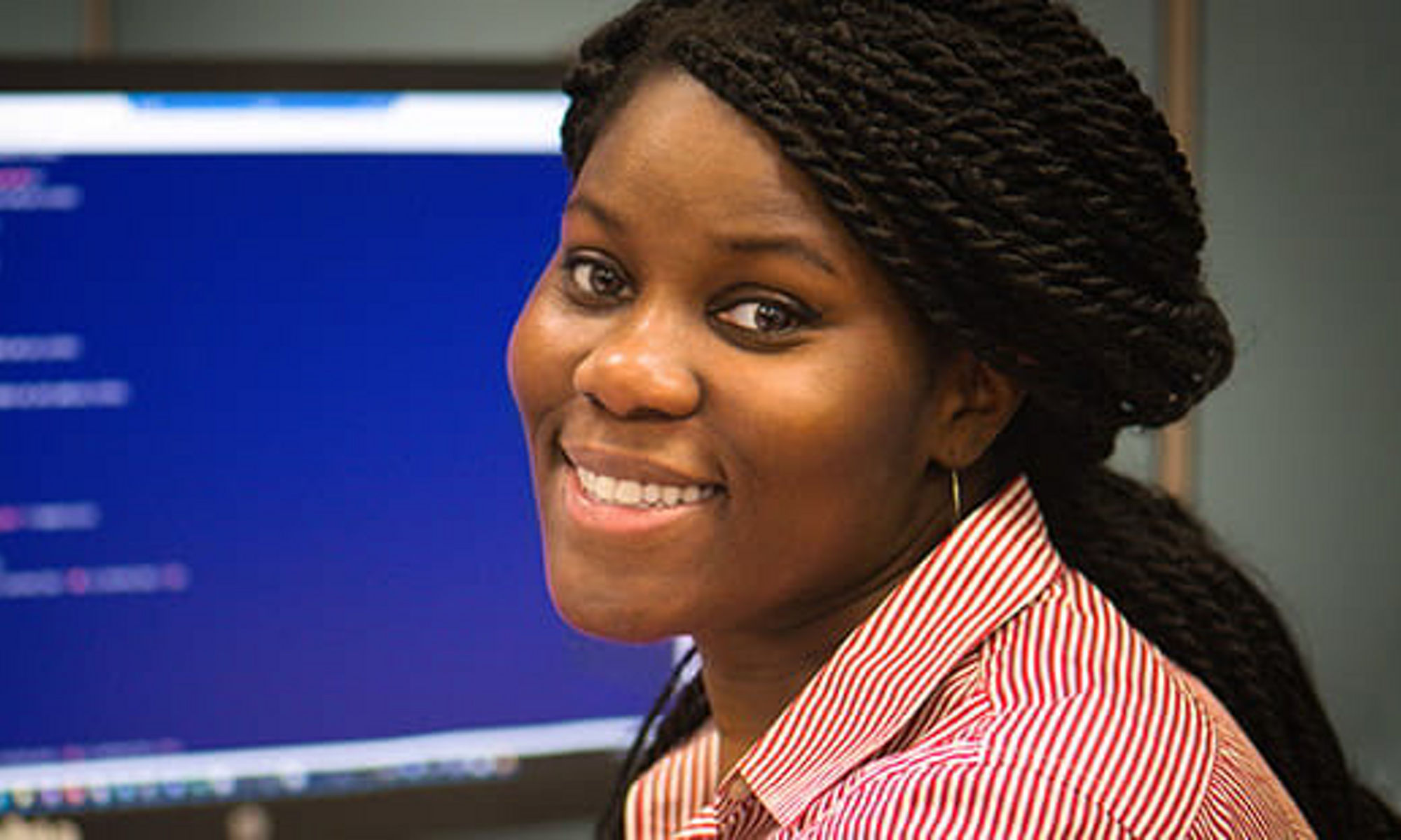 A smiling woman of color looking back from a computer screen