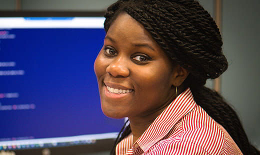 A smiling woman of color looking back from a computer screen