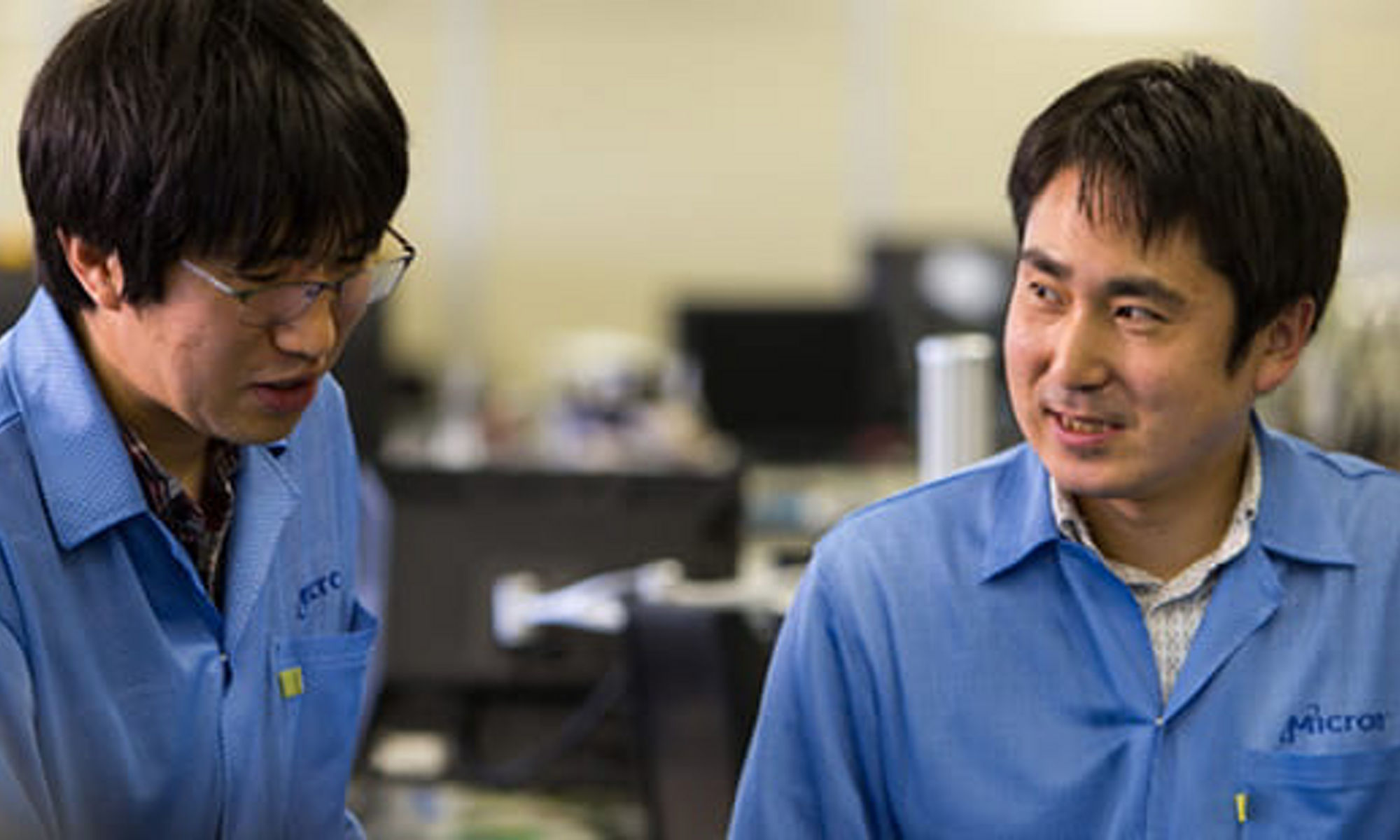 Two technicians in lab coats having a conversation.