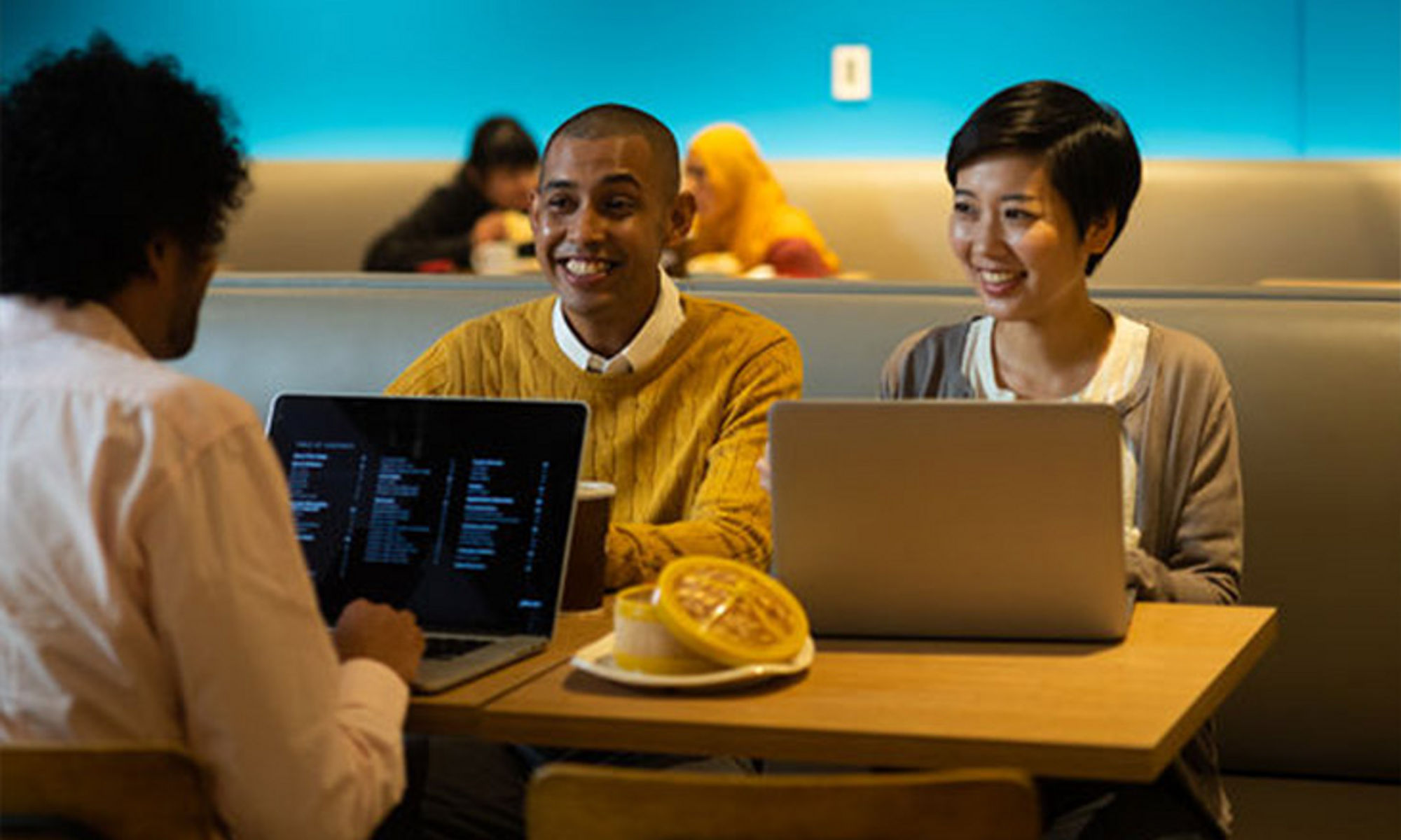 Three people at a table working on their laptops