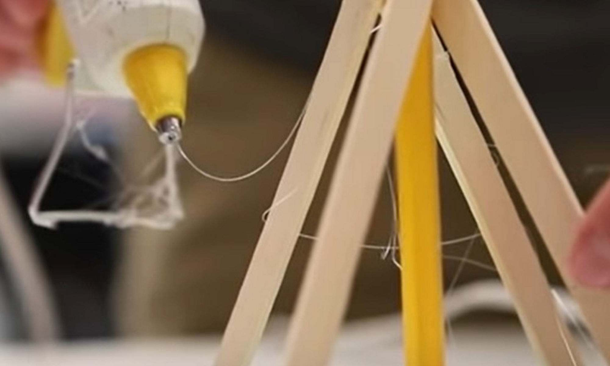 Popsicle sticks and a glue gun being used to build a teepee