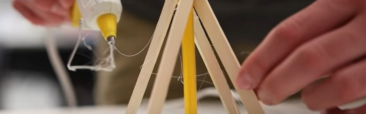 Popsicle sticks and a glue gun being used to build a teepee