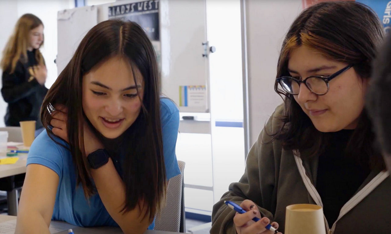 two girls sitting and working together