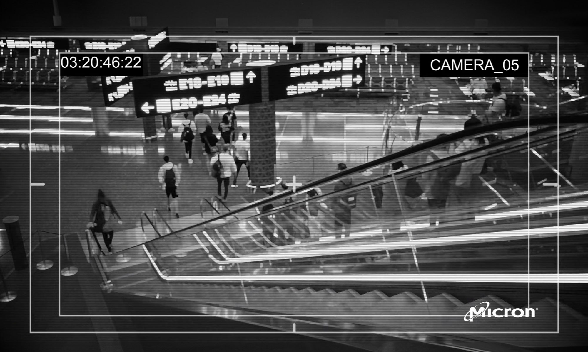 ショッピングモールのエスカレーターに設置された監視カメラのモノクロ画像 