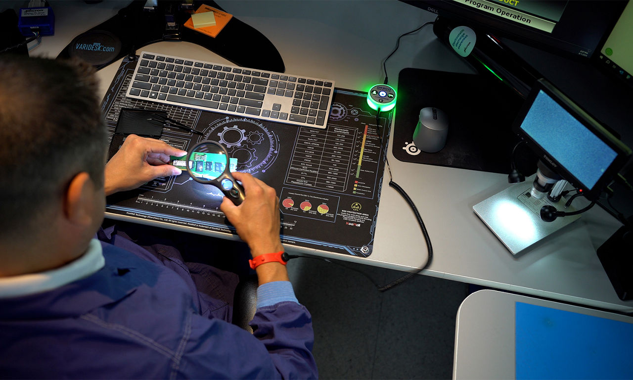 A person using a magnifier to examine a circuit component