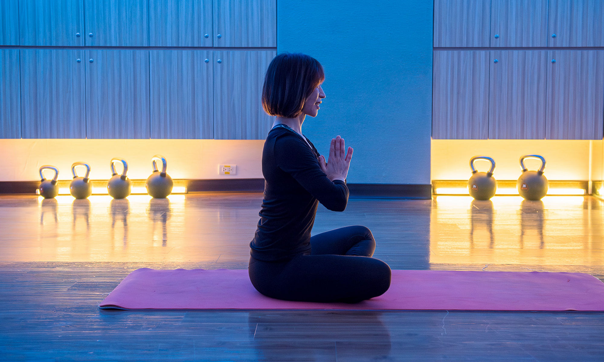 Women meditating in a low-lit gym 